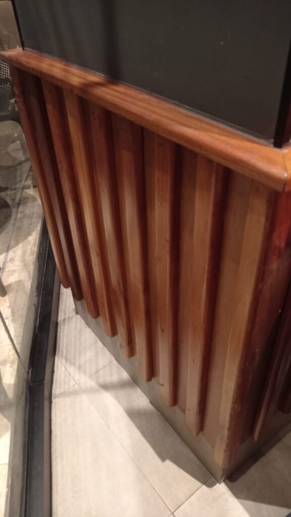 Recubrimiento de madera con listones verticales y moldura superior redondeada en la esquina de un mueble